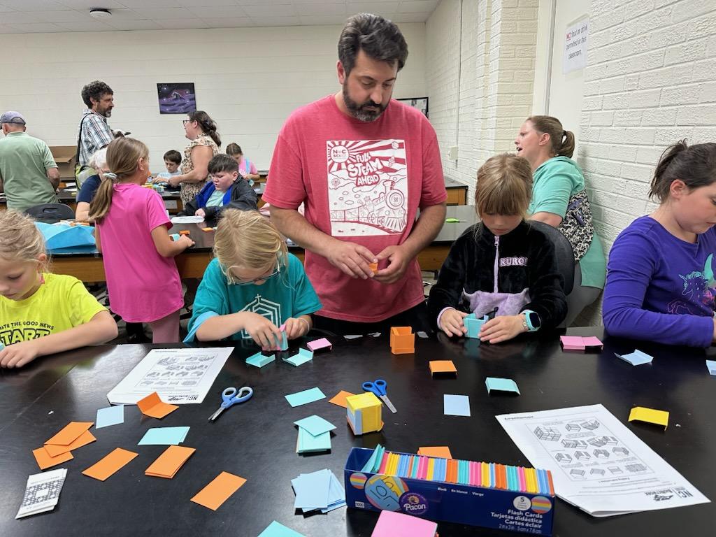 Tyler Beamer working with sticky notes and young children at SciFest.